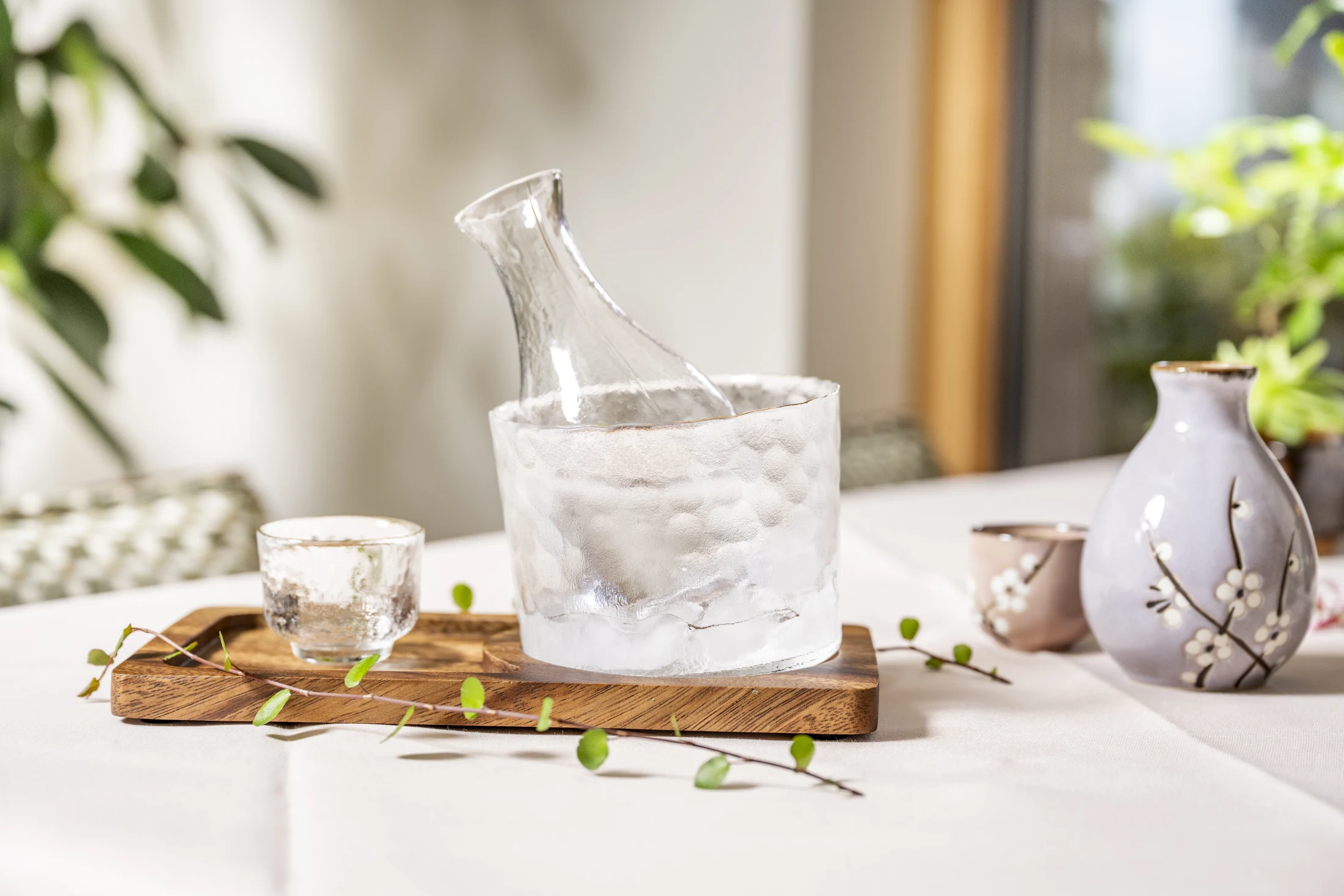 Gekühlter Sake in der Glaskaraffe auf Eis und japanische Kirschblüten-Keramik