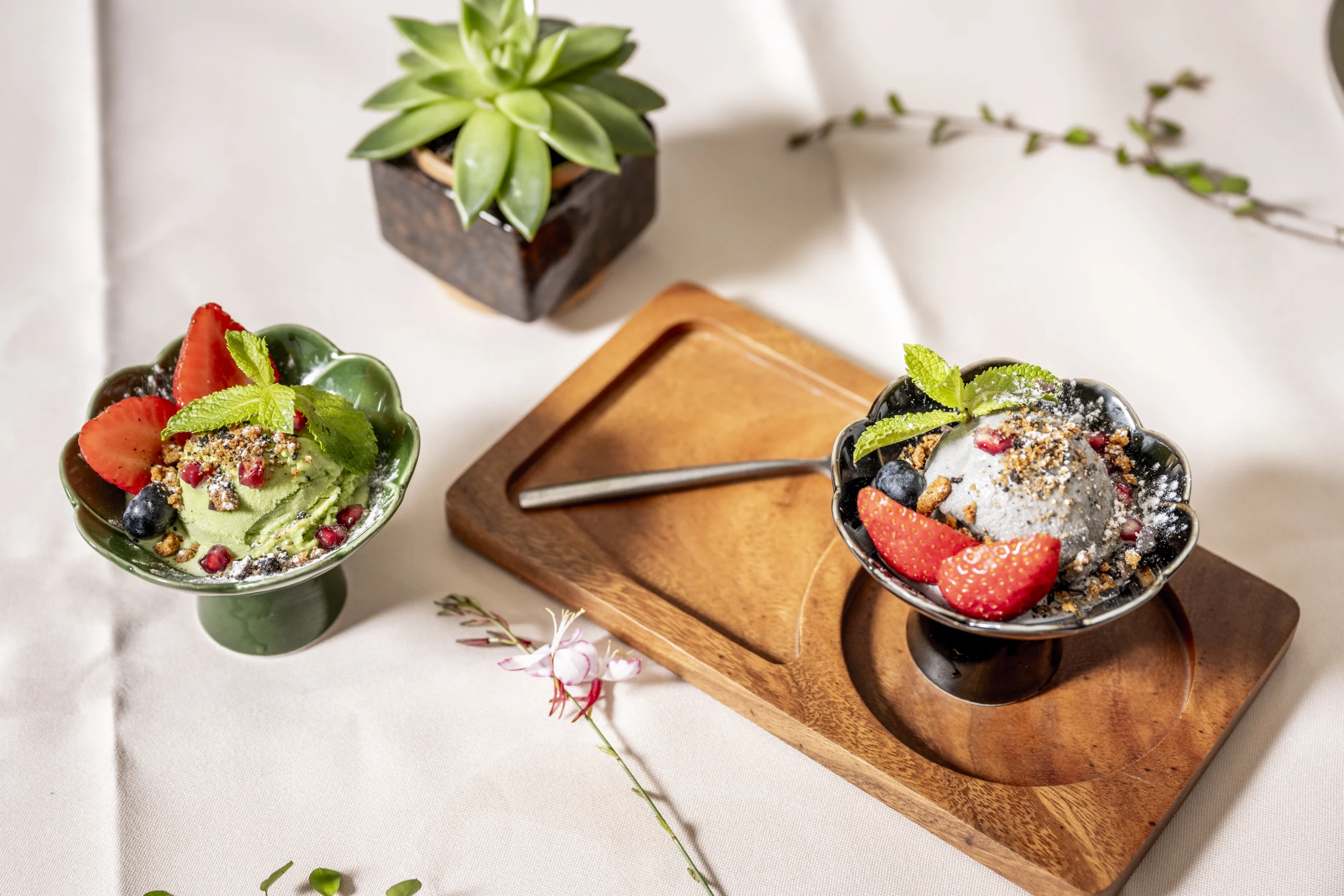 Matcha-Eis und Schwarzes-Sesam-Eis in Blüten-Keramikschalen auf Holztablett