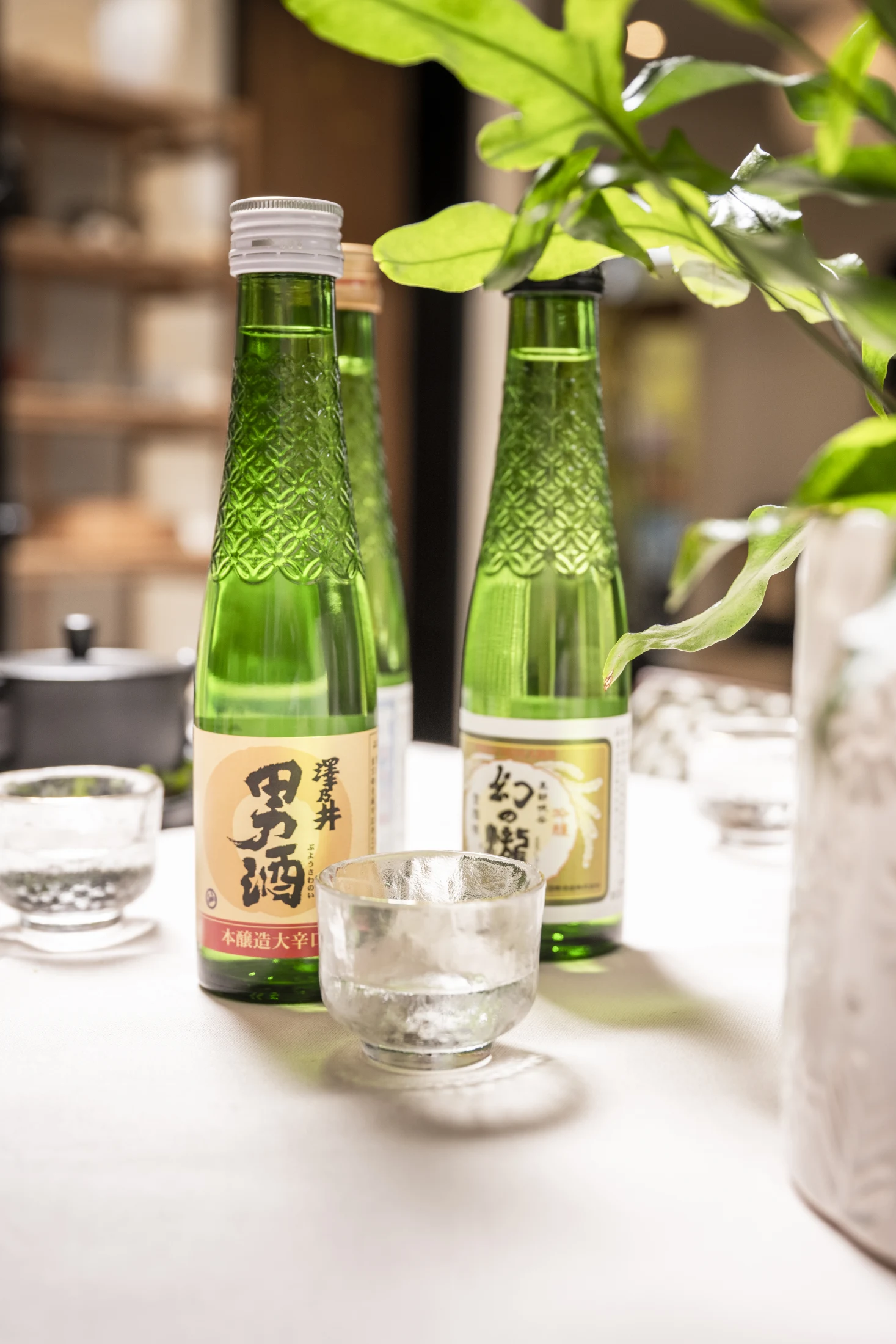 Ausgewählte japanische Sake-Flaschen in grüner Strukturglas-Optik mit Gläsern
